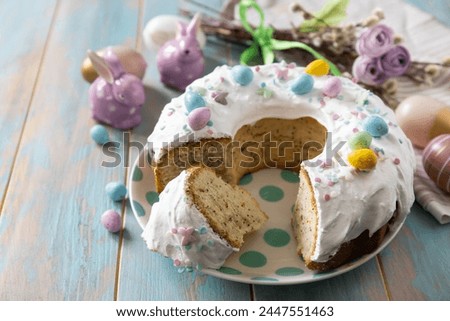 Glazed easter lemon cake decorated with confectionery and mini chocolate eggs candy on a wooden table. Happy Easter holidays, tasty dessert. Copy space.