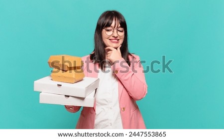 young business woman smiling with a happy, confident expression with hand on chin, wondering and looking to the side