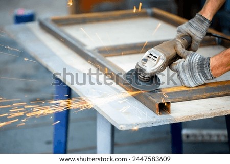 Grinding machine at work. Sparks fly from under the grinders, men's work. Dark background with copy space.