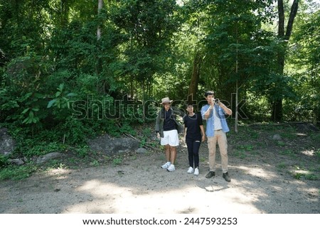 Group of three Asians, backpacking, traveling together, adventure, hiking, male friends holding cameras, taking pictures of the forest scenery while on vacation, camping, lifestyle  `concept.