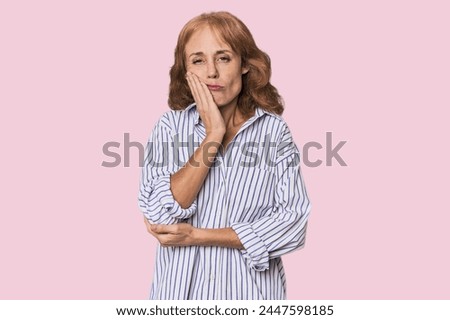 Redhead mid-aged Caucasian woman in studio who is bored, fatigued and need a relax day.