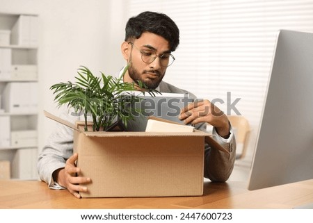 Unemployment problem. Frustrated man with box of personal belongings at desk in office Royalty-Free Stock Photo #2447600723