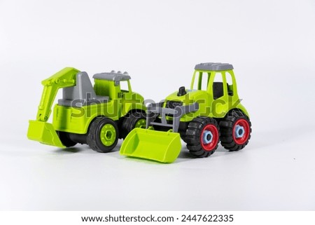 Children's toy green tractor on a white isolated background.Plastic child toy on white backdrop. Construction vehicle. Children's toy. Tractor Toy.
