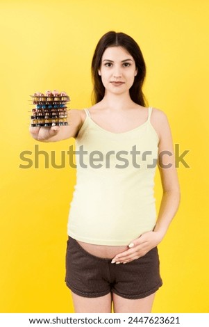 heap of blisters of pills in pregnant woman's hand at colorful background with copy space. Healthcare and treatment during pregnancy concept.