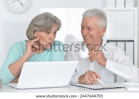 portrait of two old people working with a laptop in the office. High quality photo