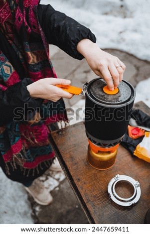 Cooking food on a burner on a hike, camping utensils compact size, pot with lid, cooking system. Woman cooking. High quality photo