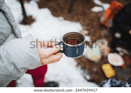Tea in kurzhka holding man on the background of the forest, drinking delicious hot drink in nature, camping in the forest, brown drink in glass, breakfast in nature. High quality photo