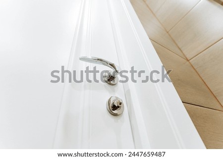 Silver chrome handle on the white bathroom door, latch on the locking mechanism. High quality photo Royalty-Free Stock Photo #2447659487