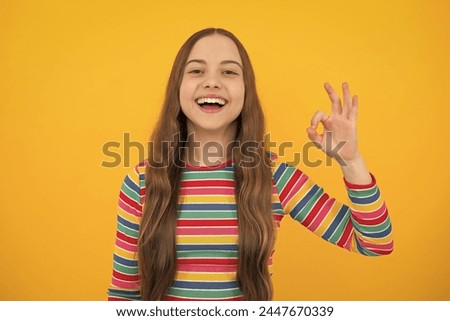 Okay. Portrait of teen girl making ok gesture, isolated background. Young teenager smiling and giving okey sign. Happy cute child showing okay.