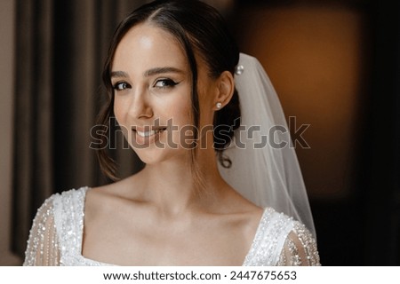 A stunning bride on her special day in a gorgeous white dress with beading and a long veil, elegant bun, flawless makeup. Picture of perfection for a beautiful, memorable wedding.