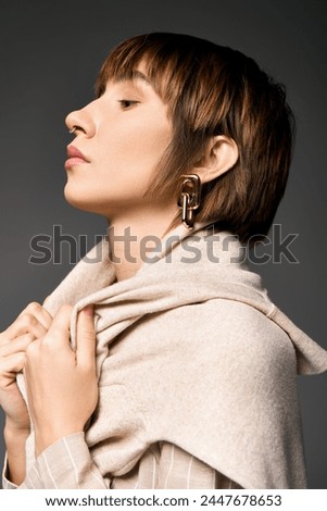 A young woman with short hair elegantly wearing a colorful scarf around her neck, exuding grace and poise.