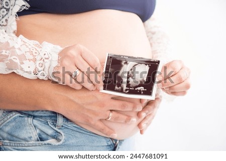 Big Pregnant belly with ultrasound echography showing baby picture motherhood