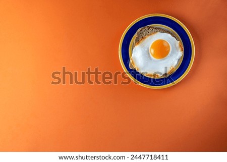 Fried egg on bread toast on a plate and on an orange background. Top view with space for text. Flat lay.
