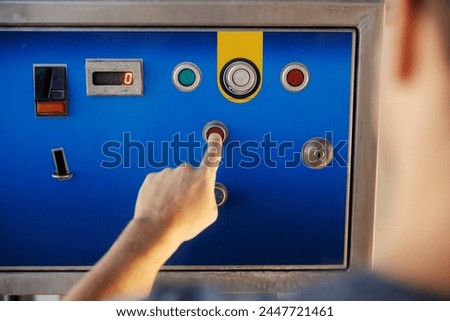 Cropped picture of worker's hand pressing button on car washing machine.