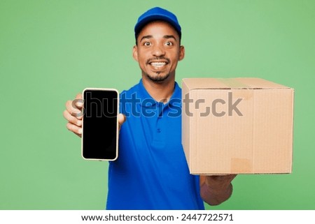 Delivery employee man wear blue cap t-shirt uniform workwear work as dealer courier hold cardboard box package use blank screen mobile cell phone isolated on plain green background. Service concept