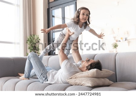 Happy young father and his little daughter playing lying on the sofa, having fun and spending time together. Happy father`s day! I love you, daddy! Parenthood, fatherhood Royalty-Free Stock Photo #2447724981