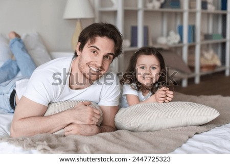 Close up portrait of a caucasian father dad lying relaxing on bed with his little daughter, dreaming and talking, looking at the camera. Spending time together, family time, father`s day Royalty-Free Stock Photo #2447725323