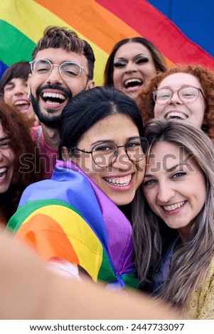 Vertical. Selfie LGBT group young people celebrating gay pride day holding rainbow flag together. Homosexual community smiling taking cheerful self portrait. Lesbian couple and friends generation z