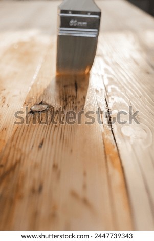  Impregnation of a wood with protective oil.Protecting the wooden surface from damage. Oil and varnish for wood.mans hand paints wooden boards with oil. Royalty-Free Stock Photo #2447739343