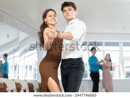 Guy and girl in couple spins to rhythm of tango during lesson for novice students. Classes in mini-groups for those who want to learn dancing