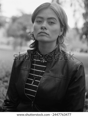 Classic monochrome portrait of of young mixed race woman looking at camera outdoors. She looks relaxed and confident and she is in a park. Film analog medium format camera.