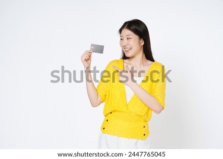Happy young Asian woman smiling, showing and pointing credit card for paying online business isolated on white background