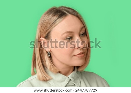 Woman with multiple ear piercing on green background