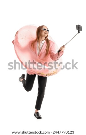 Funny young businesswoman with inflatable ring taking selfie on white background