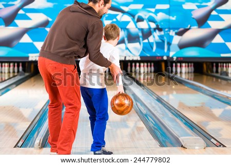 Father and son playing in bowling center