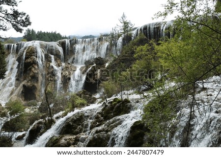 Exterior landscape natural photo view of a wild water fall of a torretn river with rocks and plants tree bushes n mountains hills in wild chinese Sichuan province  in Jiuzhaigou Valley in china, Asia