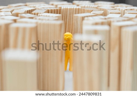 A human figure stands in the middle of high walls. Concept photo how high blockades limit the human being. Figure cries. 