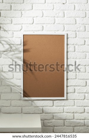 Shadow of Palm Leaves Cast on Framed Picture Against White Brick Wall