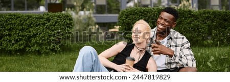 A happy African American man and Caucasian woman sitting together on grass in a park, creating a picture of joyful togetherness.