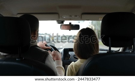 Back view of man driving car and hitting fist with little teen daughter. Close up of father with kid girl in vehicle during travel. Fun. Highway on background. Slow motion.