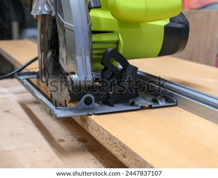 Circular saw on a DIY circular saw track, made of a long melamine wood piece and an aluminum rule. Royalty-Free Stock Photo #2447837107