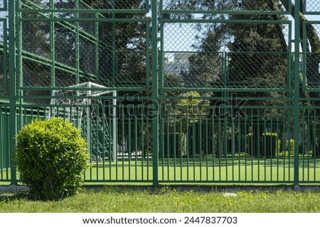 A mesh fence of green surrounds a football court in the park, summer activities in the city. High quality photo