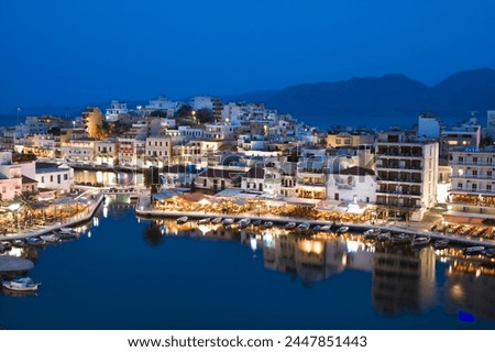View over harbour and restaurants at dusk, Ayios Nikolaos, Lasithi region, Crete, Greek Islands, Greece, Europe Royalty-Free Stock Photo #2447851443