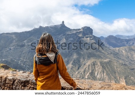 A tourist woman looking at Roque Nublo from a viewpoint on the mountain. Gran Canaria, Spain