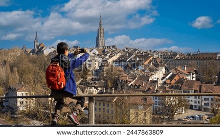 Back view young tourist man in packpack using smartphone take picture at old Town of Bern, capital of Switzerland