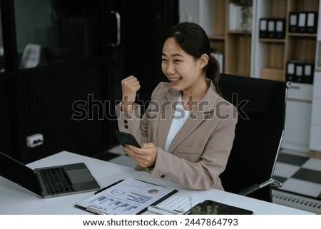 Overjoyed charming excited asian business woman worker using laptop working in office, feeling happy.