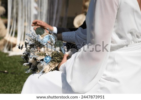 Newly married couple dressed as bride and groom, he in a black suit and she in a flowing white suit with a bouquet of flowers in her hand Royalty-Free Stock Photo #2447873951