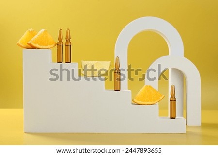 Stylish presentation of skincare ampoules with vitamin C and citrus slices on yellow background
