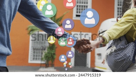 Image of social media icons floating over caucasian couple walking and holding hands. social media and communication interface concept digitally generated image.