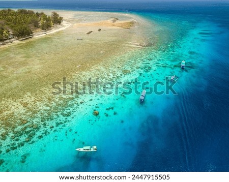Aerial view of swimmers and snorkellers from tourist boats above a tropical coral reef in a warm ocean (Gili Air, Lombok, Indonesia)
