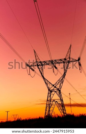 Silhouette of High voltage Transmission tower at the sunset time. Composition in vertical format. Ideal image for background uses. In Black, red and orange colors. Royalty-Free Stock Photo #2447915953