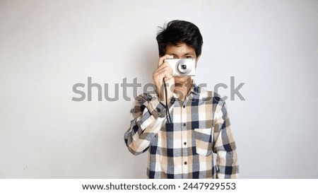 Handsome young Asian man happily taking photos using pocket camera isolated on background
