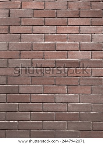 A smooth textured brown brick wall with perfectly laid bricks creating a background texture that can convey a dull and lifeless mood or an organic texture for use as a background in graphic design