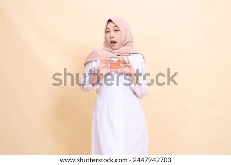 woman asian muslim in hijab shocked holding debit credit card in both hands. Lifestyle, business and finance concept