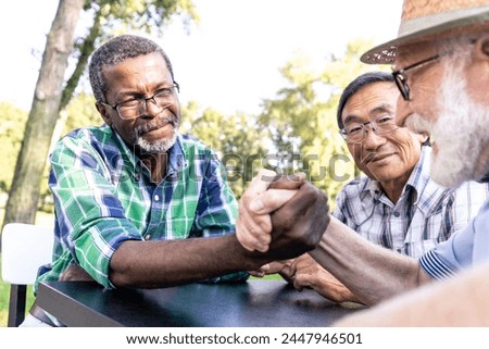 group of senior friends playing arm wrestling at the park. Lifestyle concepts about seniority and third age