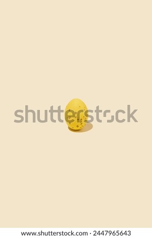 One yellow shiny Easter egg casting shadow on yellow background, minimalism concept, copy space